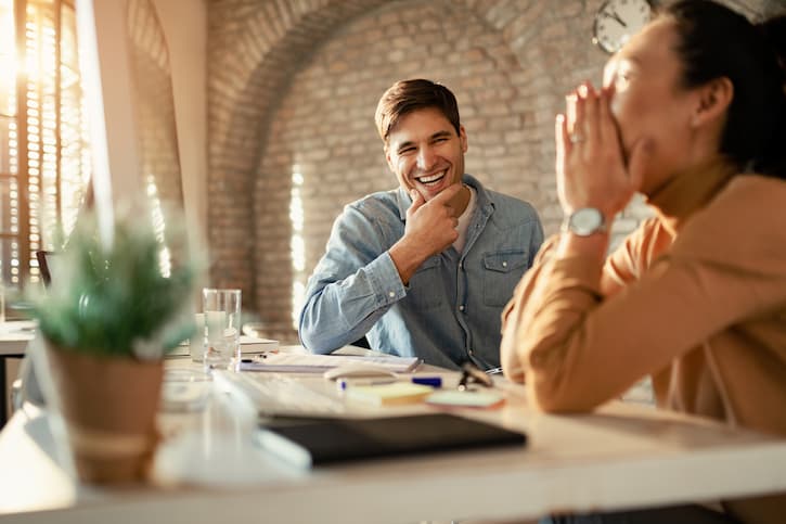 Dois consorciados estão sentados depois de acompanhar a assembleia de consórcio. Eles sorriem e estão emocionados porque foram contemplados.